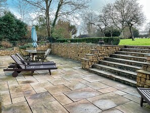 A patio with stone steps, a table with chairs, and a blue umbrella. - 3 bedroom accommodation in Bradford Abbas (Bradford Abbas)
