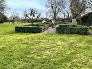 Un jardin bien entretenu, avec des haies soigneusement taillées et un chemin central.