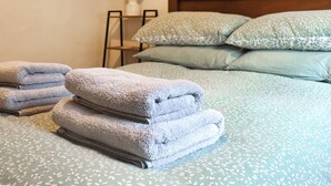A neatly made bed with folded towels, a lamp, and patterned pillows. - Stable Cottage - UK51203 (Fishguard)