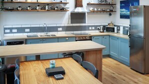 A modern kitchen with wooden cabinets, a central island, and stainless steel appliances. - Stable Cottage - UK51203 (Fishguard)