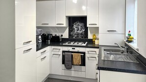 A modern kitchen with white cabinets, a black countertop, a gas stove, and a dishwasher. - 2 bedroom accommodation in Westwood, near Margate (Westwood, near Margate)