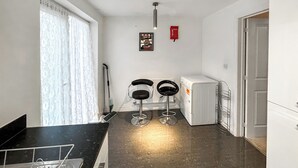 A kitchen with a black countertop, two bar stools, a refrigerator, and a window with curtains. - 2 bedroom accommodation in Westwood, near Margate (Westwood, near Margate)