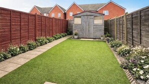 A well-maintained backyard with a neatly trimmed lawn, a wooden shed, and a tall wooden fence. - 2 bedroom accommodation in Westwood, near Margate (Westwood, near Margate)