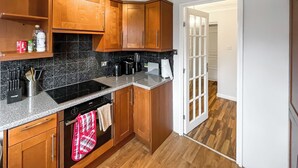 A kitchen with wooden cabinets, a granite countertop, a stove, and a dishwasher. - 3 bedroom accommodation in Sittingbourne (Sittingbourne)