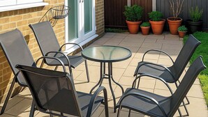 An outdoor patio with a round glass table and six metal chairs. - 3 bedroom accommodation in Sittingbourne (Sittingbourne)