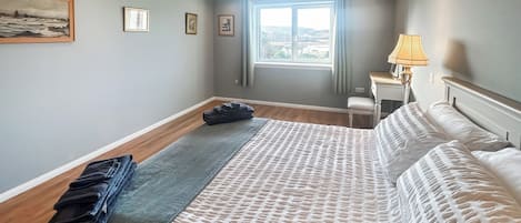 Une chambre d’hôtel avec un lit, un bureau, une chaise, une fenêtre avec des rideaux et une lampe.