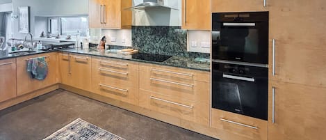 Una cocina moderna con armarios de madera, una campana extractora de acero inoxidable y un refrigerador negro.