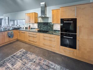A modern kitchen with wooden cabinets, a stainless steel range hood, and a black refrigerator.