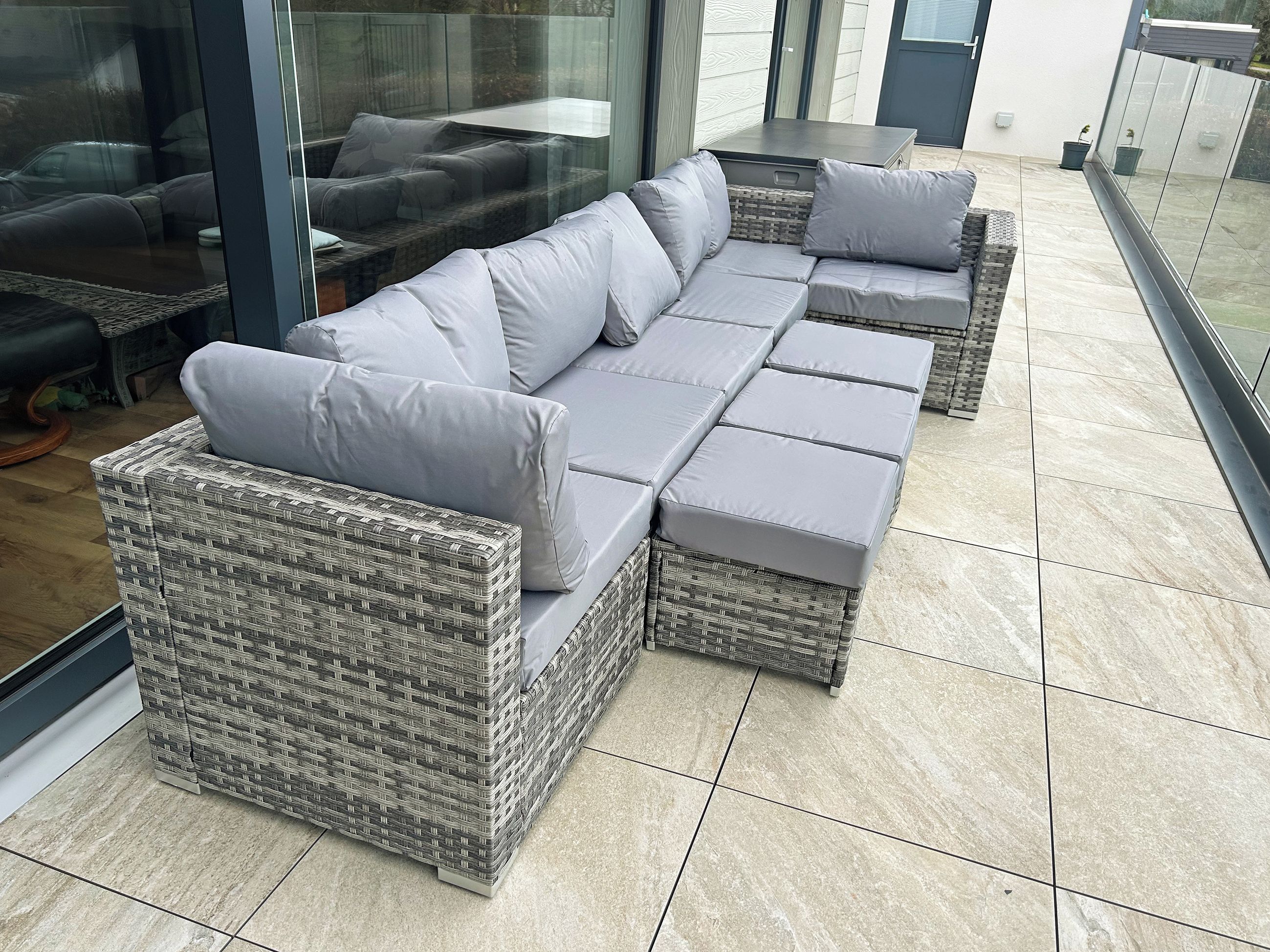 Un sofá modular con cojines, una mesita y una planta en maceta en un entorno exterior moderno.