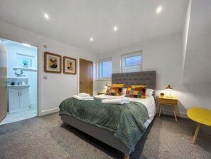 A bedroom with a bed, bedside table, lamp, and a view of the bathroom. - 2 bedroom accommodation in Whitby (Whitby)
