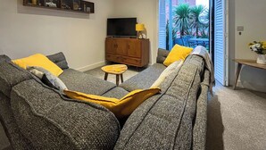 Ein Wohnzimmer mit einer Couch, einem Fernseher, einem Schrank und einem kleinen Tisch.