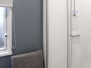 Ein Badezimmer mit Wandmuster, Handtuchhalter und Duschabtrennung.
