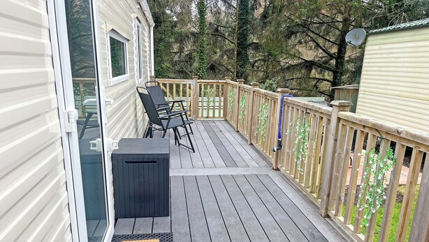 A wooden deck with a welcome mat, a trash bin, and outdoor furniture. - 2 bedroom accommodation in Wisemans Bridge (Wisemans Bridge)