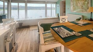 Una habitación con un ventanal grande que da a una masa de agua, una mesa de comedor con individuales y un radiador.