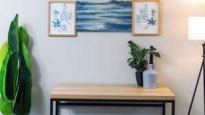 Um quarto com um banco de madeira, uma planta em vaso e quadros na parede.