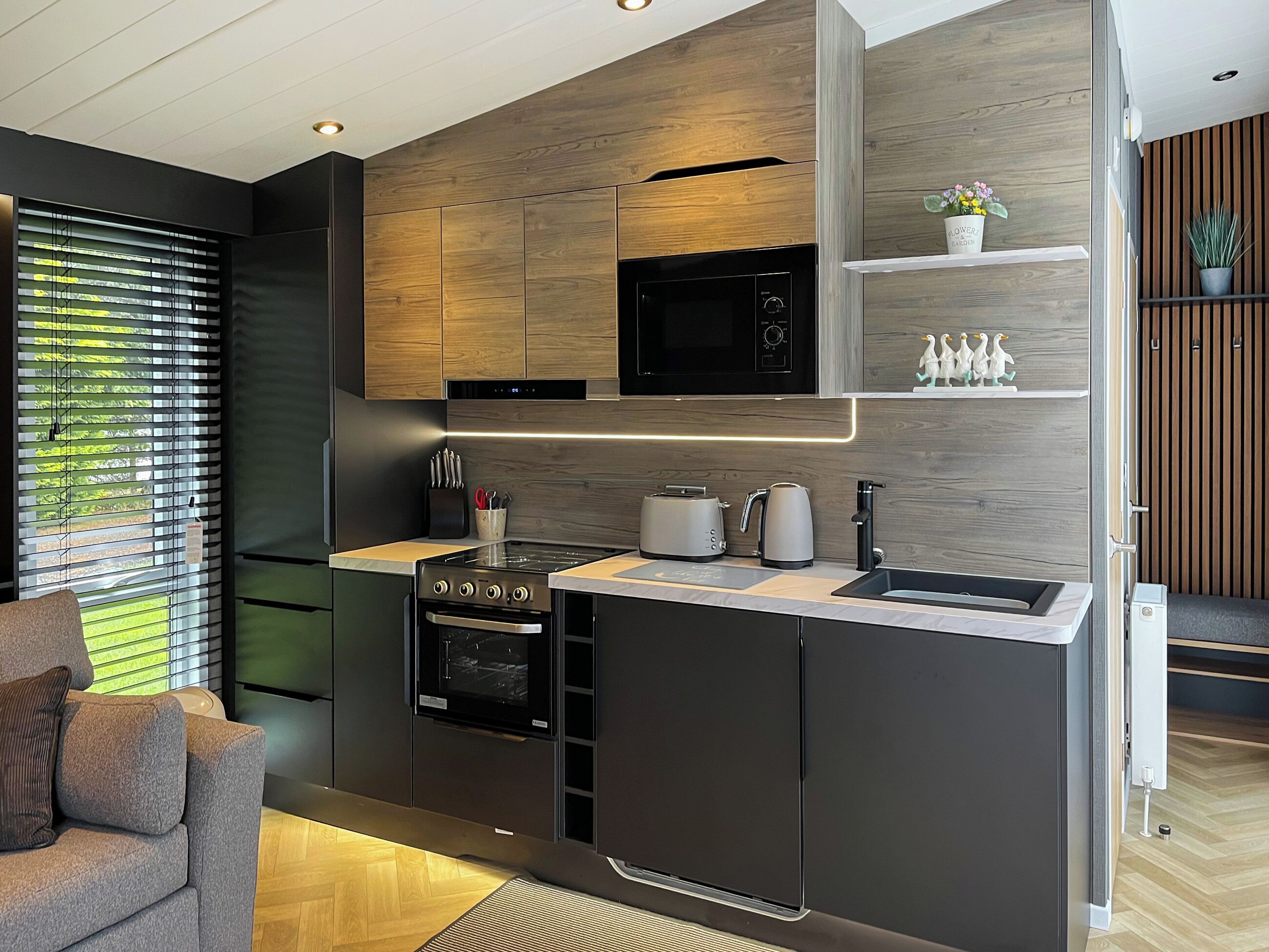 Eine moderne Küche mit eingebauten Geräten, einer Holzwand und einer kleinen Arbeitsplatte mit Spüle.