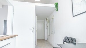 Et moderne, minimalistisk rum med en hvid dør, et lille bord og en stol.