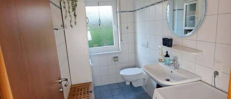 Ein kleines Badezimmer mit Toilette, Waschbecken und Waschmaschine.
