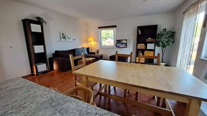 Un ampli espai de sala d'estar amb una gran taula de dinar de fusta, un sofà i una televisió.