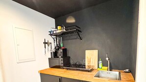 Una cocina compacta con encimera de madera, protector contra salpicaduras negro y horno empotrado.