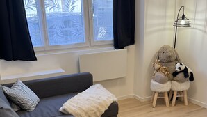 A modern living room with a grey sectional sofa, a white fluffy throw, and a small wooden stool with stuffed animals. - Comfort in Le Mont-Dore - Pets allowed (Mont-Dore)