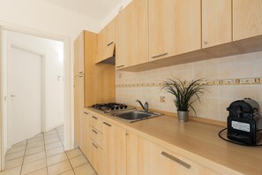 Eine Küche mit Holzausstattung, einem Edelstahl-Spülbecken, einem Gasherd und einer Kaffeemaschine.