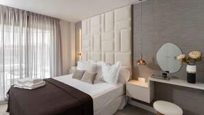 Ein modernes Schlafzimmer mit einem großen Bett, einem Nachttisch, einem Spiegel und einem kleinen Hocker.