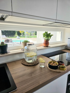 Un comptoir de cuisine avec un grand bocal en verre, une plante en pot, un bol de collations et un verre d’eau.