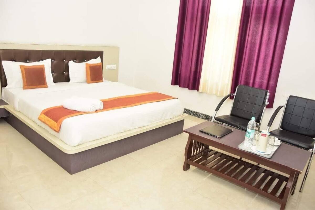 A hotel room with a bed, a desk, and two chairs.