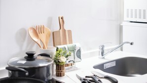 Une cuisine avec une marmite noire, des ustensiles en bois, un couteau et un évier.