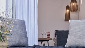A modern room with a built-in hot tub, grey cushions, a small table with glasses and bottles, and pendant lighting.
