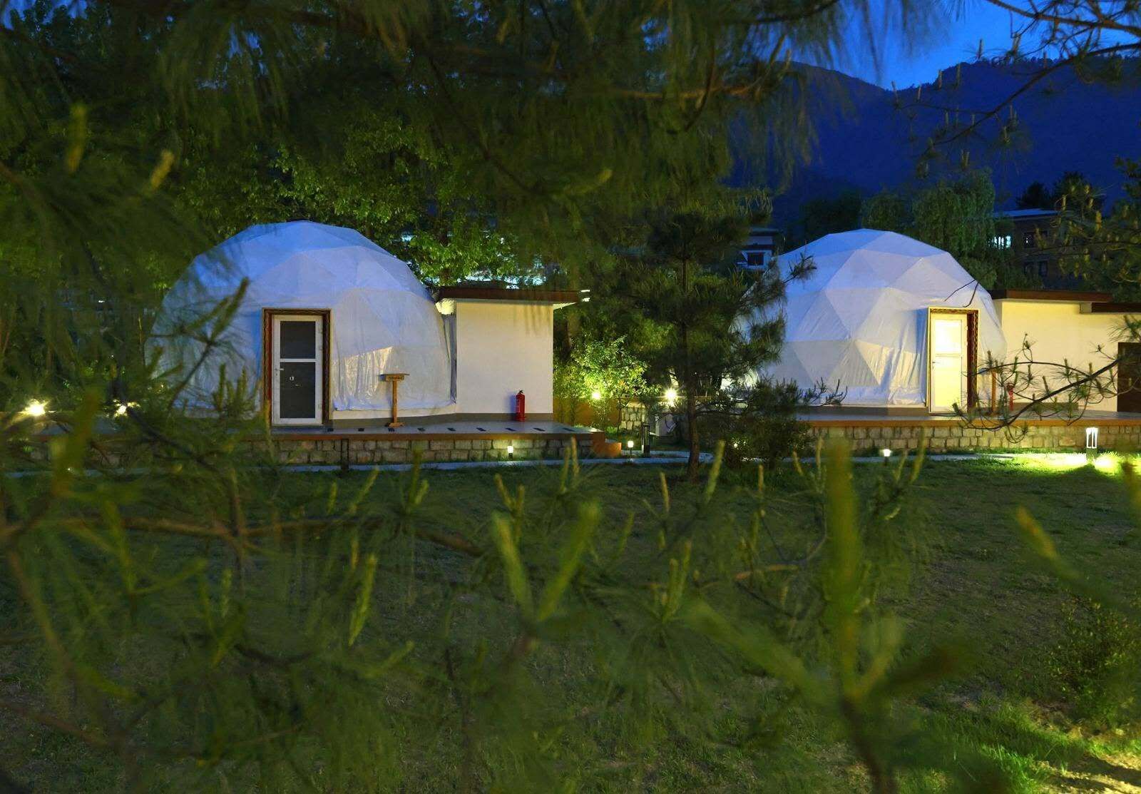 Two dome-shaped tents with doors, a small table, and a fire extinguisher.