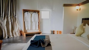 Una habitación de hotel con cama, un banco de madera, un armario y una ventana.