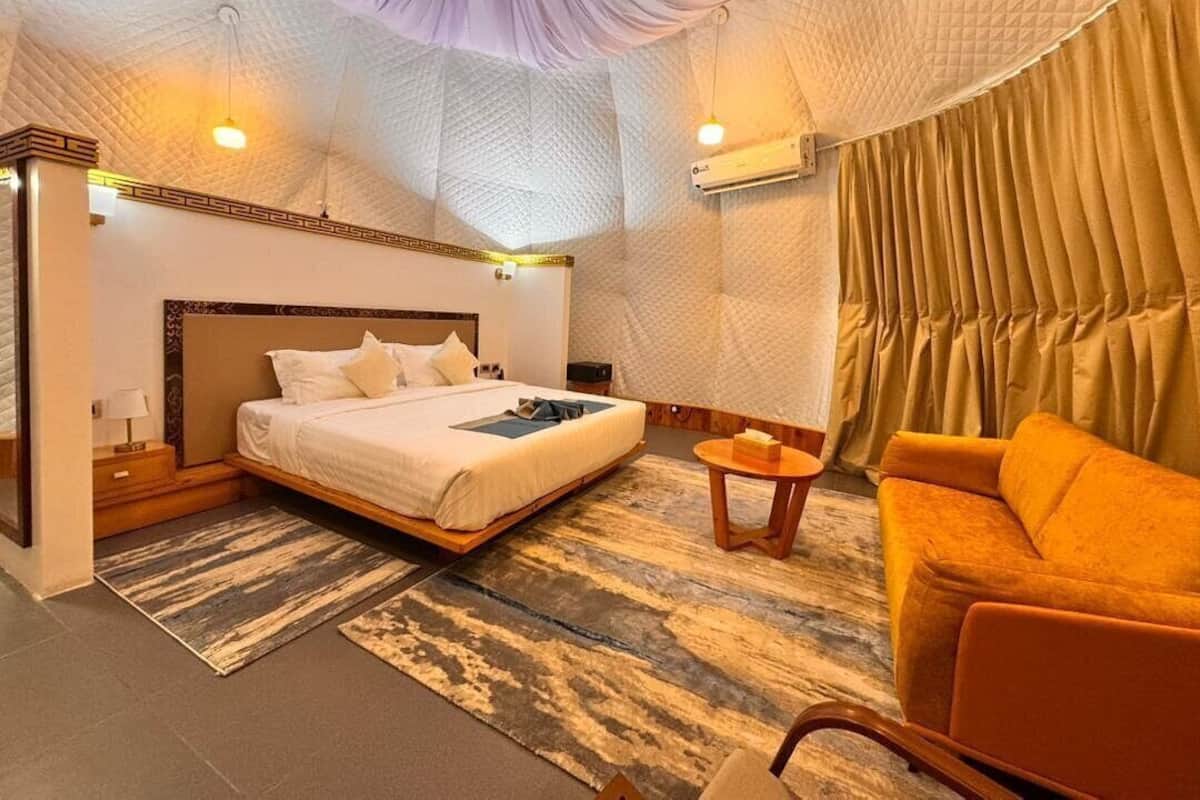 Une chambre à coucher avec un grand lit, un canapé, une petite table et un climatiseur fixé au mur.