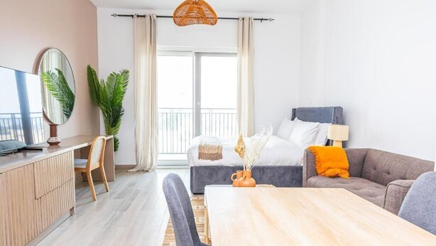 Moderni hotellihuone, jossa on suuri sänky, sohva, ruokapöytä ja televisio.