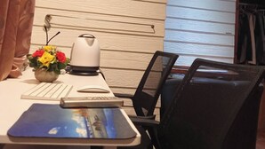 Moderni toimistotila, jossa on puuseinä, työpöytä tietokoneella, tuoli ja maljakko täynnä kukkia.