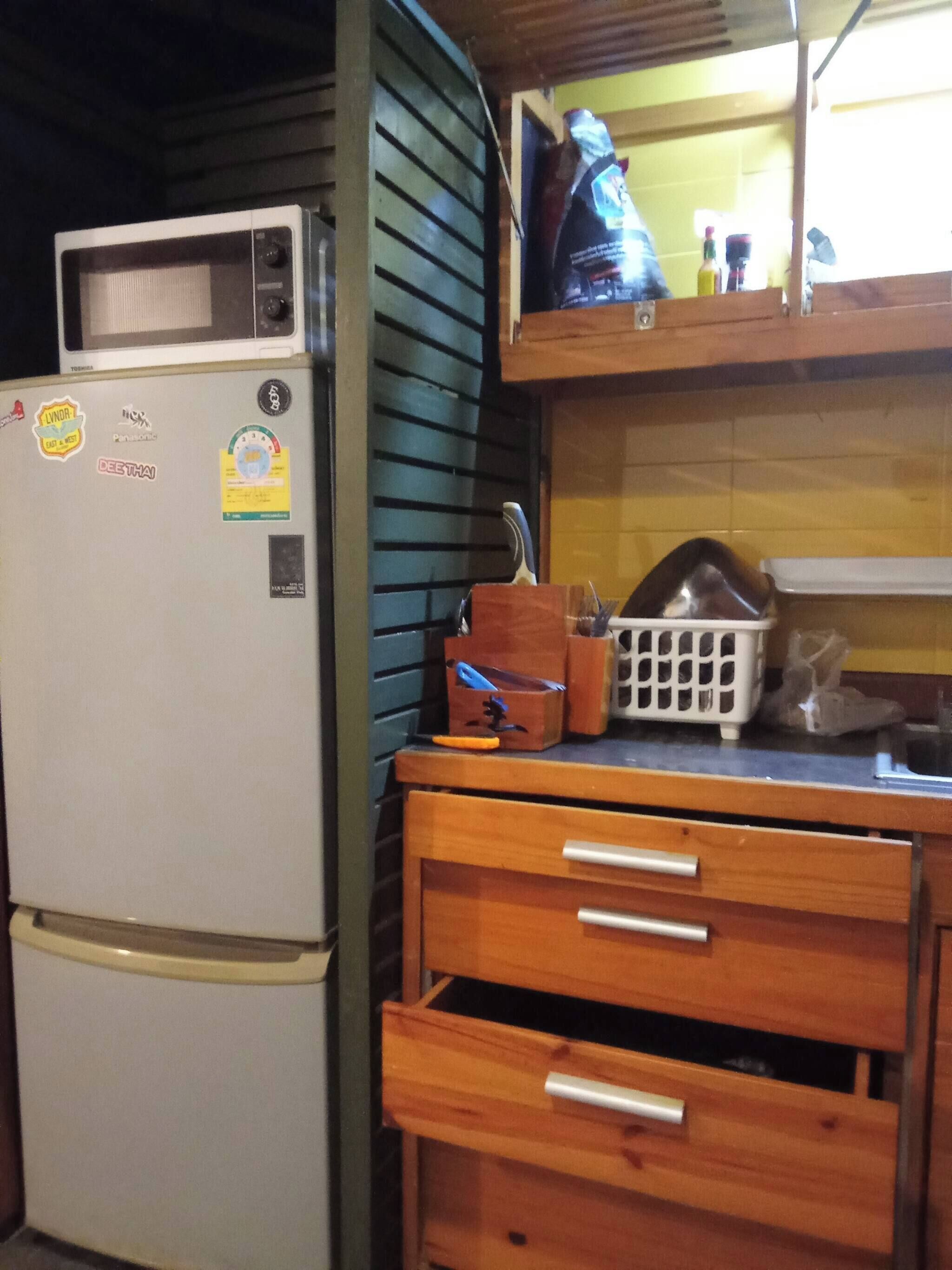 A compact kitchen with a white refrigerator, wooden cabinets, and a microwave.