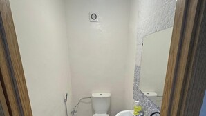 A small bathroom with a toilet, sink, and a mirror. - Charming 3-Bedroom Apartment Near Menara Garden (Marrakesh)