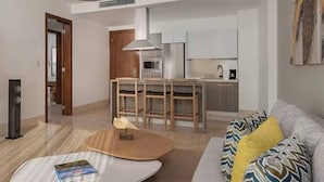 A modern living room with a flat-screen TV, a coffee table, and a sofa with patterned cushions. - Crown Penthouse - Luxury & Views   All inclusive (Puerto Plata)