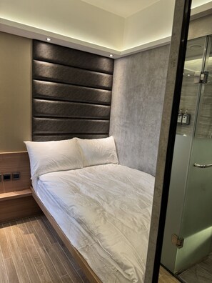 A modern bedroom with a bed, a headboard, and a glass shower enclosure. - M plus (Kowloon)