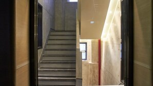 Una escalera que sube a un piso superior, con vista a una ventana y una puerta al final.