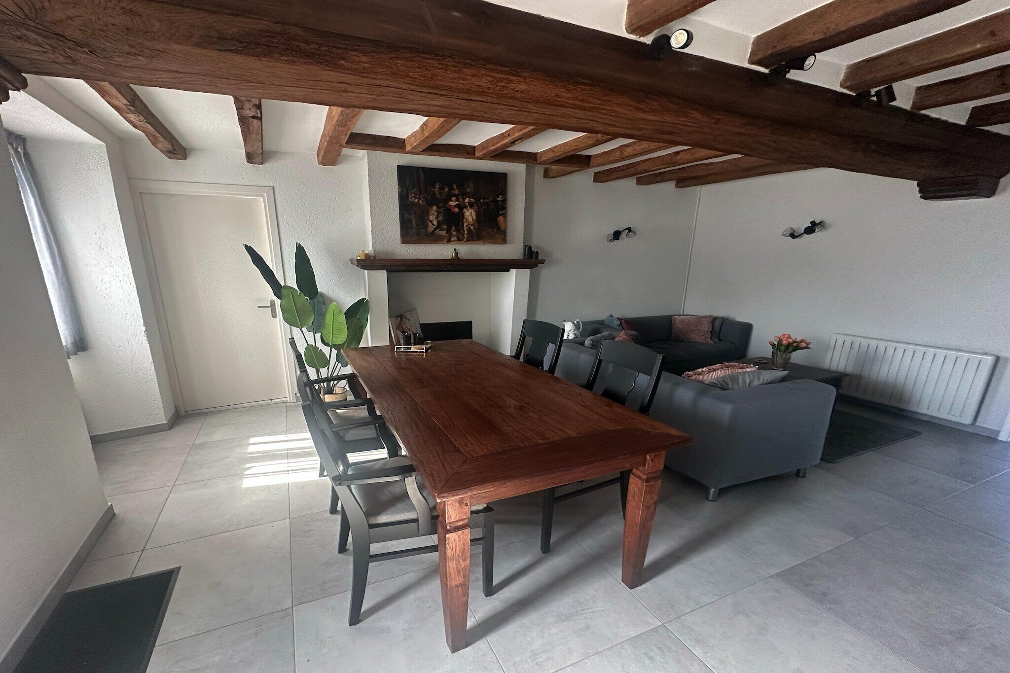 Ein Essbereich mit Holztisch und -stühlen, einer grauen Couch und einem Kamin.