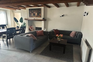 A living room with a sofa, coffee table, and a painting on the wall. - Lovely Holiday Home in Loire for 10 (Mauges sur Loire)