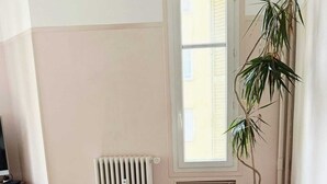 A dining area with a black table, clear chairs, a radiator, a window, and a potted plant. - Nice center 4-room apartment with air conditioning (Nice)