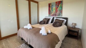 A bedroom with a bed, pillows, a nightstand, a lamp, and a painting on the wall. - Villa Big view (Roquebrune-sur-Argens)