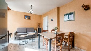 Een eethoek met een tafel, stoelen, een bank en een kroonluchter.