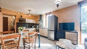 Een moderne keuken met een eetgedeelte, een grote koelkast en een flatscreen televisie.