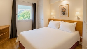 A neatly made bed with white linens, a wooden headboard, and two bedside lamps. - Cocon près de la Baule (Saint-André-Des-Eaux)
