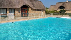 A swimming pool with a stone building in the background. - Cocon près de la Baule (Saint-André-Des-Eaux)