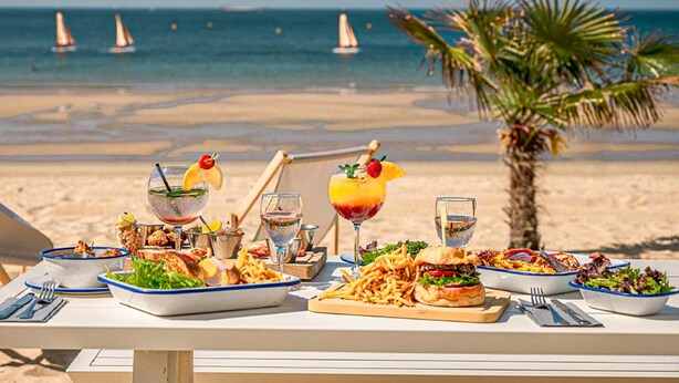 A beachside dining table with various dishes and drinks, overlooking the ocean with sailboats in the distance. - Cocon près de la Baule (Saint-André-Des-Eaux)
